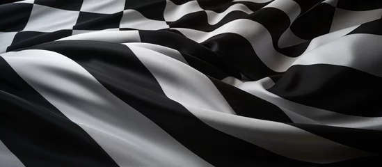 Deurstickers A detailed closeup shot of a monochrome checkered flag fluttering in the wind, showcasing the bold pattern in black and white © AkuAku