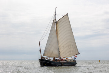 Traditional old wooden flat bottomed boat on the World Heritage Wadden Sea, the Netherlands. Calm water and blue Dutch skies, brown sails.