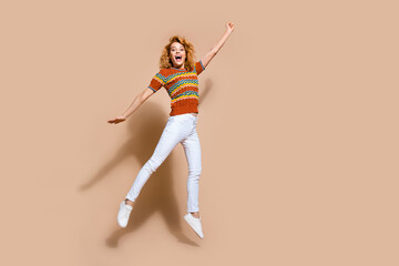 Fototapeta na wymiar Photo portrait of lovely young lady jumping superhero fly dressed stylish striped garment isolated on beige color background