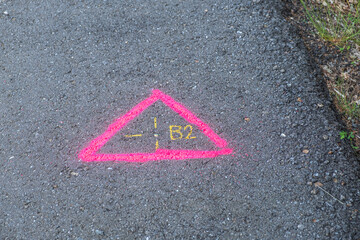 Pink geodetic mark on the asphalt, topography marking painted on a road