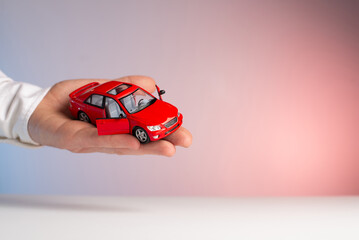 Red toy car in man hand. Sale car - obrazy, fototapety, plakaty