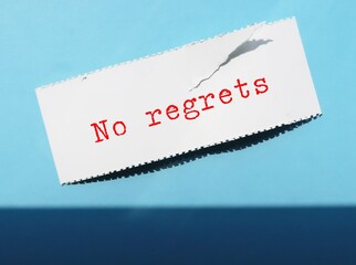 On blue background, torn paper with text written NO REGRET - to live a life without feeling bad...