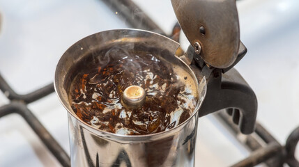 Macchinetta (ekspres do kawy) - parzenie kawy metodą tradycyjną na kuchence gazowej. Świeżo parzona kawa bąbelkuje w dzbanku tradycyjnego stalowego ekspresu do kawy, rozsiewając piękny aromat. - obrazy, fototapety, plakaty