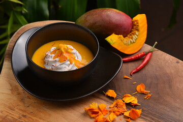 Thai spicy pumpkin, mango and coconut milk soup with kaffir lime leaves , red chilli and galangal roots powder. Vegan, healthy food, gluten-free.