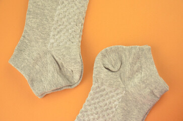 New textured gray cotton socks on an orange background closeup