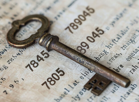 A photo of an old key with the numbers "789045" engraved on it, lying in front of a page filled with large and small numbers, 