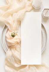 Vertical Card near cream fabric knot and ring on plates top view copy space, wedding mockup