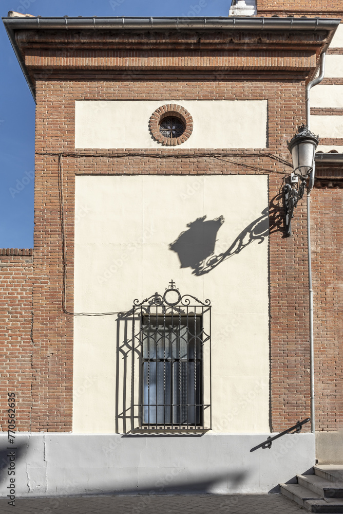 Wall mural detail of church facade with small window with black metal wrought iron bars