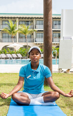 Fototapeta na wymiar Woman of color practicing yoga by the pool.