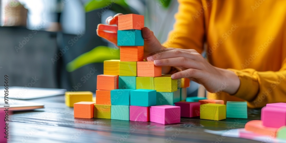 Poster close-up of hands building a tower with colorful blocks on a table