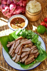 Thai Grilled Pork Neck with spicy dipping sauce and sticky rice with thai vegetables, Isan food, thai kitchen background 