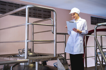A food safety officer in professional attire diligently takes notes while inspecting stainless...
