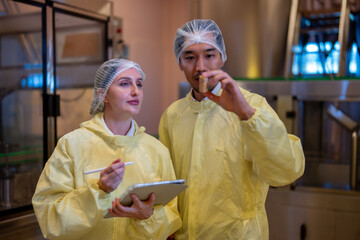 Quality control specialists in a cleanroom inspecting samples and recording data on a tablet to...