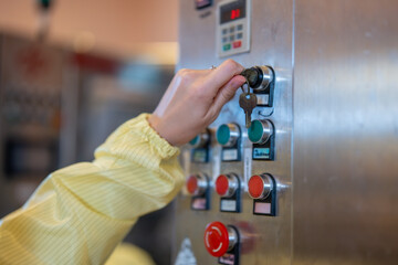 A female operator in a cleanroom suit attentively adjusts the control panel of a beverage bottling...