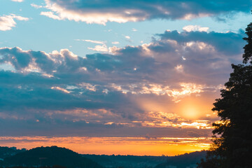 Powerful Sunrise shining through the clouds in the sky early in the morning