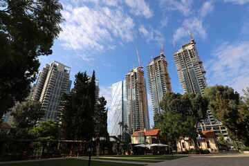 Tel Aviv Israel 03/28/2024. Buildings and structures of Tel Aviv through the foliage of tall trees.