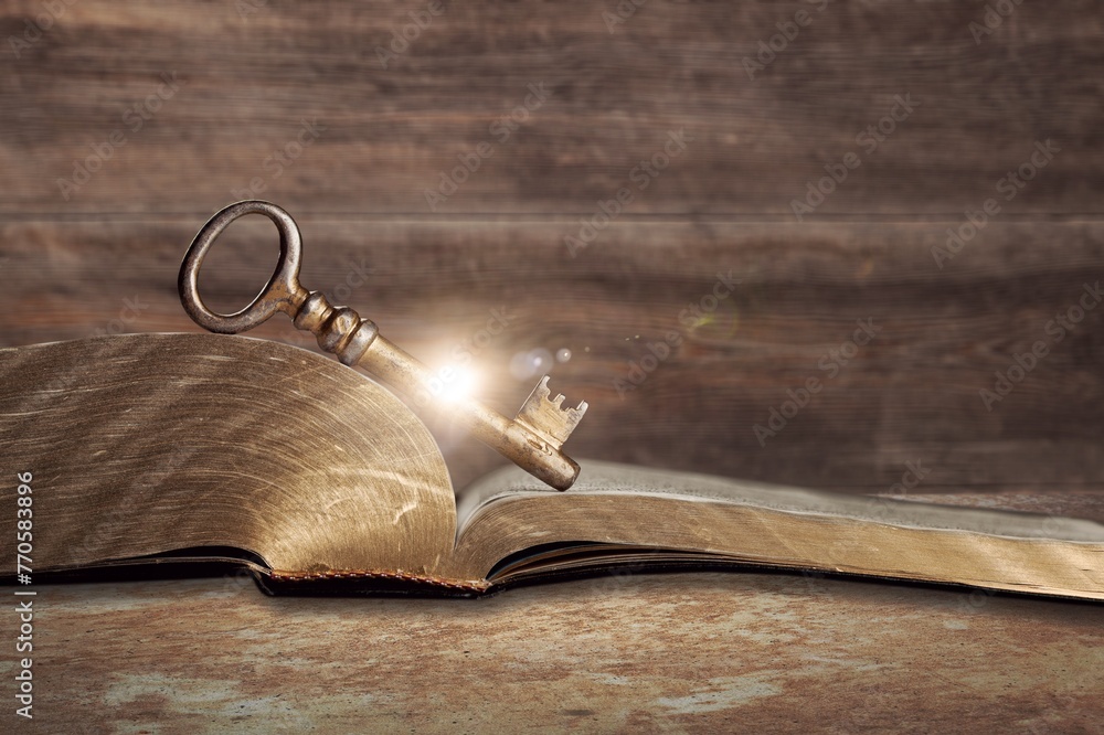 Canvas Prints image of open book with vintage key on wooden table