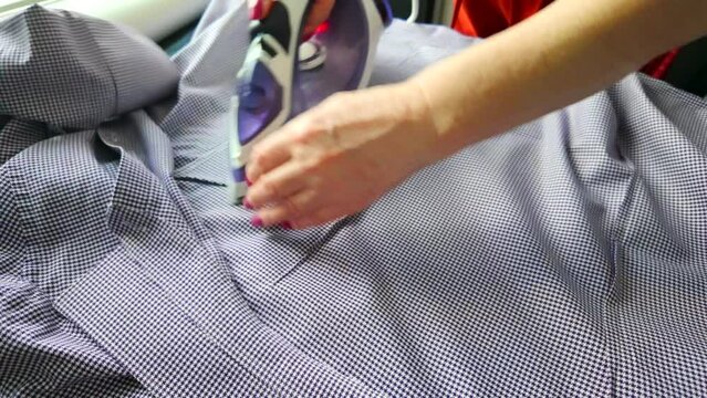 Top view woman ironing white t-shirt clothes at home. Doing household chores concept.