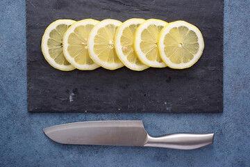 Lemon slices on a slate plate and kitchen knife - 770589431