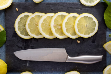Lemon slices on a slate plate and kitchen knife - 770589438