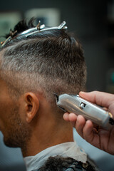 cutting a gray-haired man's hair with a clipper