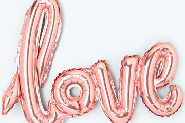 Word Love. Closeup of pink foil inflatable balloon on a blue background.