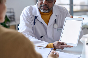 Close up of doctor holding digital tablet with blank white screen and demonstrating health...