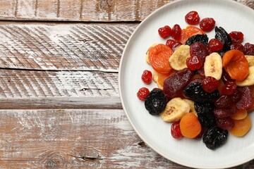 Mix of delicious dried fruits on wooden table, top view. Space for text
