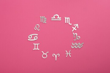 Zodiac signs on pink background, flat lay. Space for text