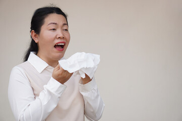 Asian woman is sneezing, open mouth, holds white tissue paper. Concept, Health problems. Ill, sick...