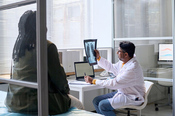 Side view portrait of Middle Eastern senior doctor looking at chest x ray during consultation in...