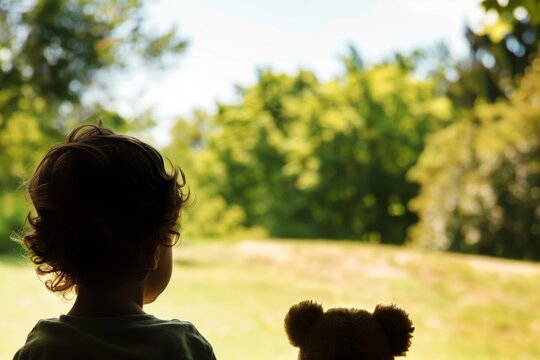 child looking at soft toy on distant park hill