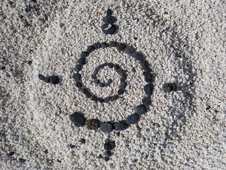 Spiral pattern with black volcanic stones on whitish gravel. Ammonite cast fossil. Elegant...