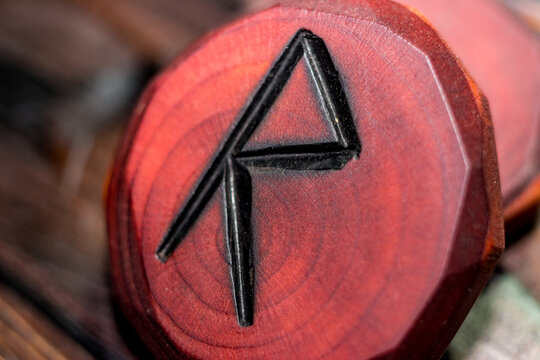 Rune Raido red color carved from wood on a wooden background - Elder Futhark