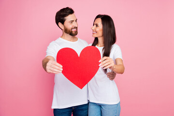 Fototapeta na wymiar Photo portrait of nice young couple look each other hold big red heart postcard wear trendy white outfit isolated on pink color background