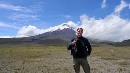 Solo traveler and the Cotopaxi active volcano in Ecuador, South America, hiking tour to the mountain with a snow peak, beautiful landscape.