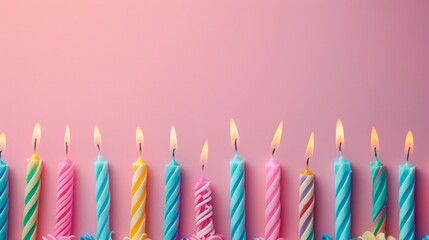 Vibrant lit birthday candles in multiple colors lined up on a pink background signaling the jubilation of a celebration