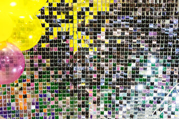 A mosaic background of silver glitter tiles with a yellow balloon behind it. The tiles add a playful and festive atmosphere to the scene.