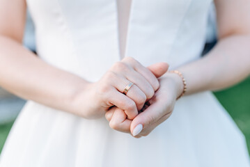 bride holds hands together with wedding ring