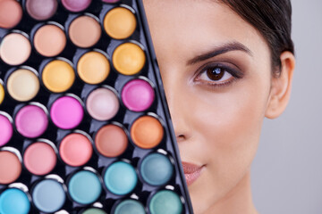 Eyeshadow, makeup palette and portrait of woman in studio for cosmetics, powder and foundation on gray background. Closeup, beauty and female model with cosmetology product, facial glow and skincare