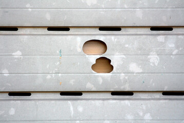Closeup of two large hail damage holes on family house dirty old plastic PVC roller shutters after...