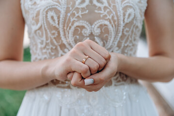 bride holds hands at wrist with wedding ring