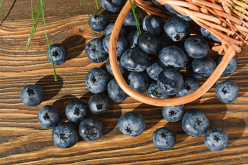 Blueberries spilled out of a basket on a wooden brown table