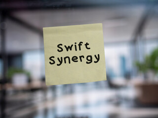 Post note on glass with 'Swift Synergy'.