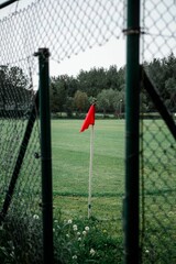 red flag and white pole sticking out of fenced in grassy area