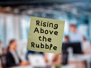 Post note on glass with 'Rising Above the Rubble'.