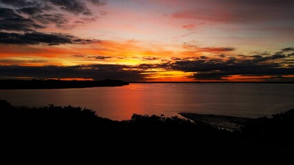 Orange sunset casts a reflective glow upon the tranquil Bucklands Beach, Auckland, New Zealand