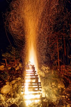 Vertical image of a large, blazing bonfire, with bright orange and yellow flames