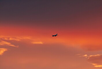 Scenic view of an airplane flying in the sky at pink sunset