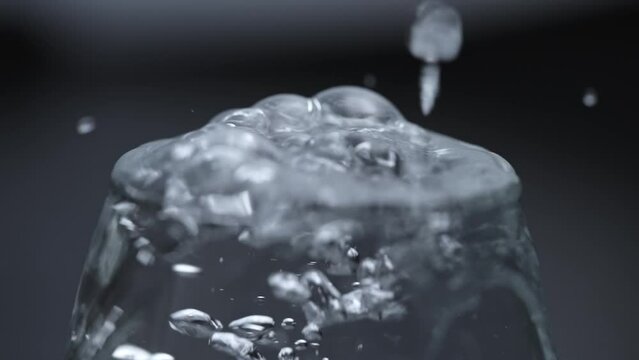 フルHD240pスーパースロー映像：ガラスコップにに水を注いで溢れる水面のアップ